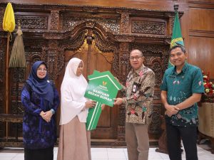 Bupati Banyumas Sadewo Tri Lastiono menyerahkan simbolis kunci rumah berbentuk replika kunci hijau kepada warga penerima manfaat program RTLH Baznas di Ruang Joko Kaiman.