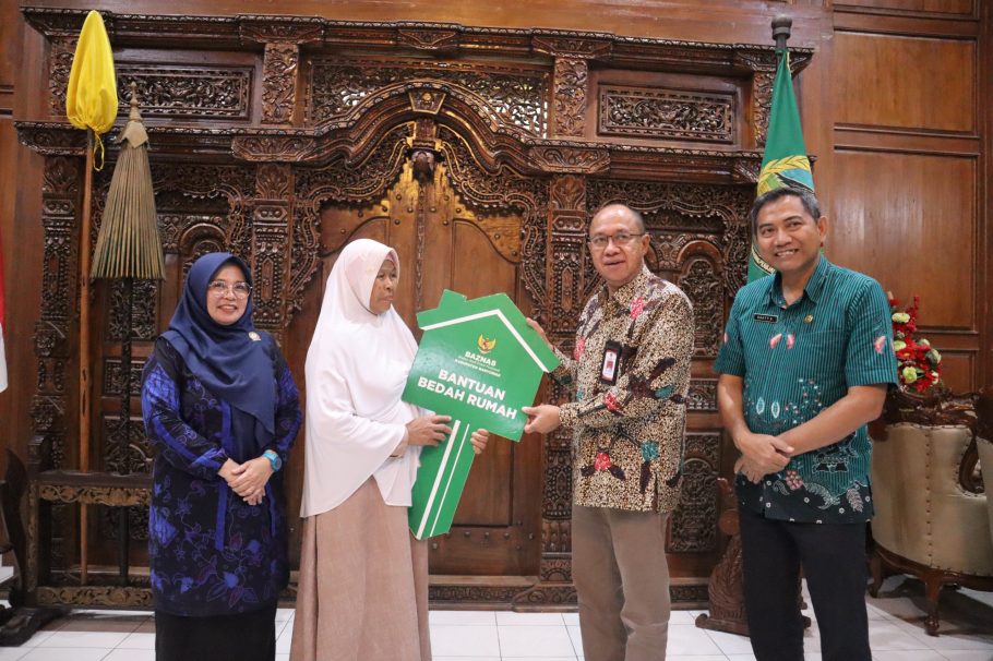 Bupati Banyumas Sadewo Tri Lastiono menyerahkan simbolis kunci rumah berbentuk replika kunci hijau kepada warga penerima manfaat program RTLH Baznas di Ruang Joko Kaiman.