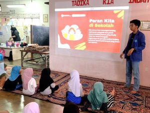 Mahasiswa STMIK Widya Utama Purwokerto sedang memberikan presentasi materi edukasi peran pencegahan bullying di sekolah kepada anak-anak Pekerja Migran Indonesia yang duduk lesehan di Sanggar Belajar Malaysia.