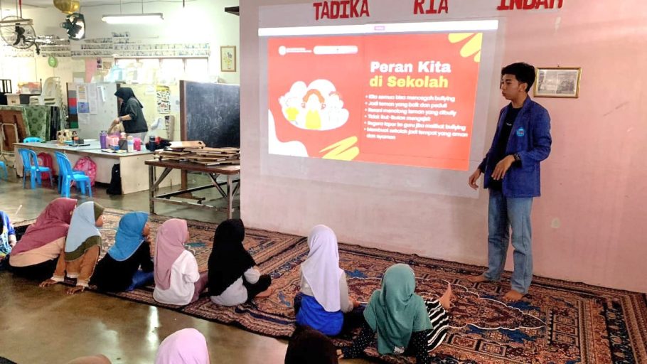 Mahasiswa STMIK Widya Utama Purwokerto sedang memberikan presentasi materi edukasi peran pencegahan bullying di sekolah kepada anak-anak Pekerja Migran Indonesia yang duduk lesehan di Sanggar Belajar Malaysia.