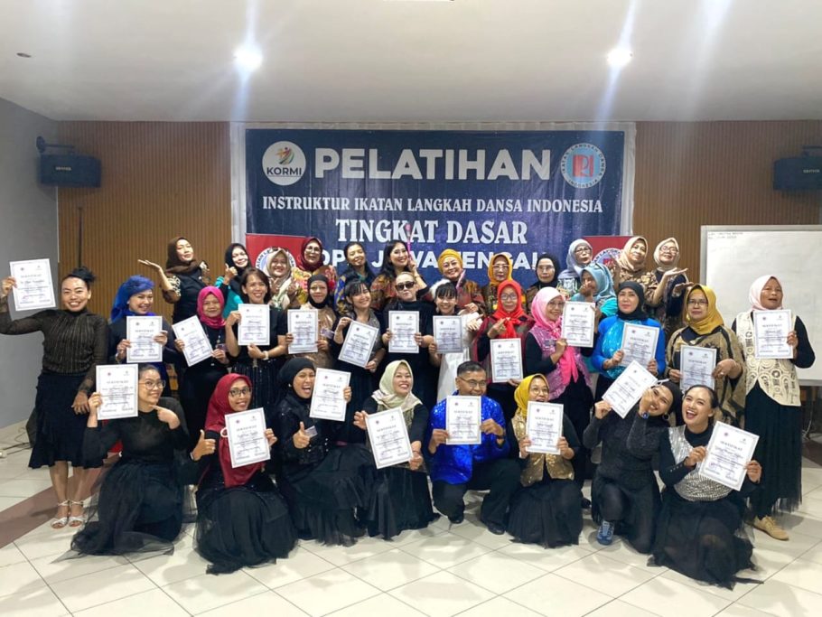 Foto bersama para peserta wanita dan pria memegang sertifikat kelulusan dalam ujian instruktur dansa tingkat dasar ILDI Kabupaten Banyumas di depan spanduk kegiatan.