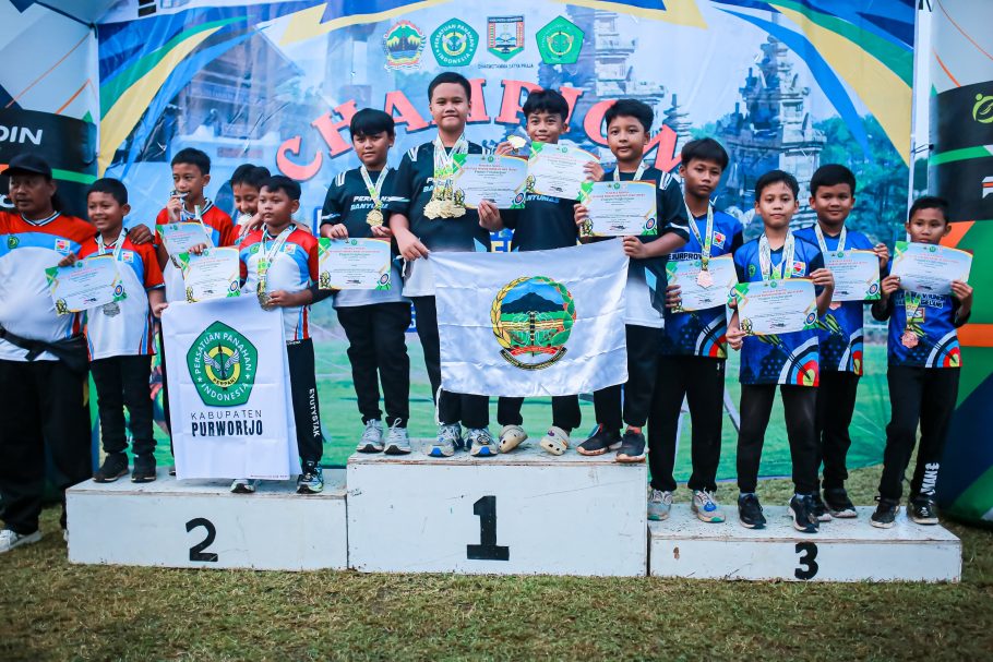 Foto bersama deretan atlet cilik panahan Kabupaten Banyumas di atas podium juara satu, dua, dan tiga sambil memegang piagam penghargaan dan mengibarkan bendera lambang daerah Perpani Banyumas pada Kejurprov Panahan Junior Jateng 2026.