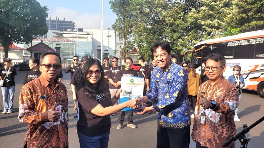 Staf Ahli Bupati Banyumas Arif Triyanto menyerahkan dokumen pelepasan kepada Ketua LPPD Banyumas Pendeta Febe Rustini di halaman Pendopo Si Panji, berlatar belakang bus kontingen dan anggota tim.