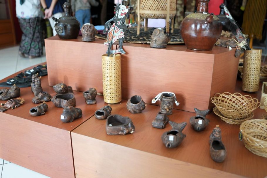 Berbagai produk kerajinan tangan lokal seperti anyaman bambu, wayang, dan gerabah tanah liat dipajang di rak kayu galeri UMKM Griya Kriya Dekranasda Banyumas.