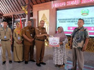 Bupati Banyumas Sadewo Tri Lastiono menyerahkan bantuan sosial secara simbolis kepada ahli waris penderes kelapa di Pendopo Si Panji