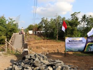 Spanduk ground breaking penggantian Jembatan Sungai Lopasir di Kecamatan Jatilawang Banyumas dengan latar belakang kondisi jembatan lama yang runtuh.