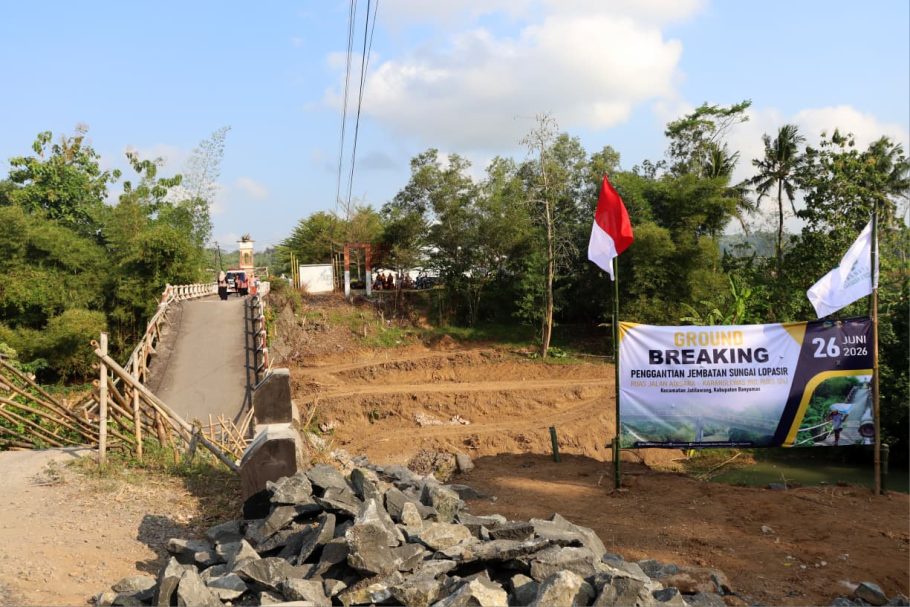 Spanduk ground breaking penggantian Jembatan Sungai Lopasir di Kecamatan Jatilawang Banyumas dengan latar belakang kondisi jembatan lama yang runtuh.