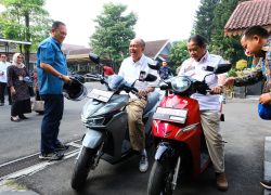 Bupati Banyumas Sadewo Tri Lastiono tertawa saat mencoba sepeda motor listrik VinFast warna abu-abu di Pendopo SiPanji Purwokerto.