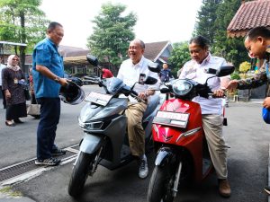 Bupati Banyumas Sadewo Tri Lastiono tertawa saat mencoba sepeda motor listrik VinFast warna abu-abu di Pendopo SiPanji Purwokerto.