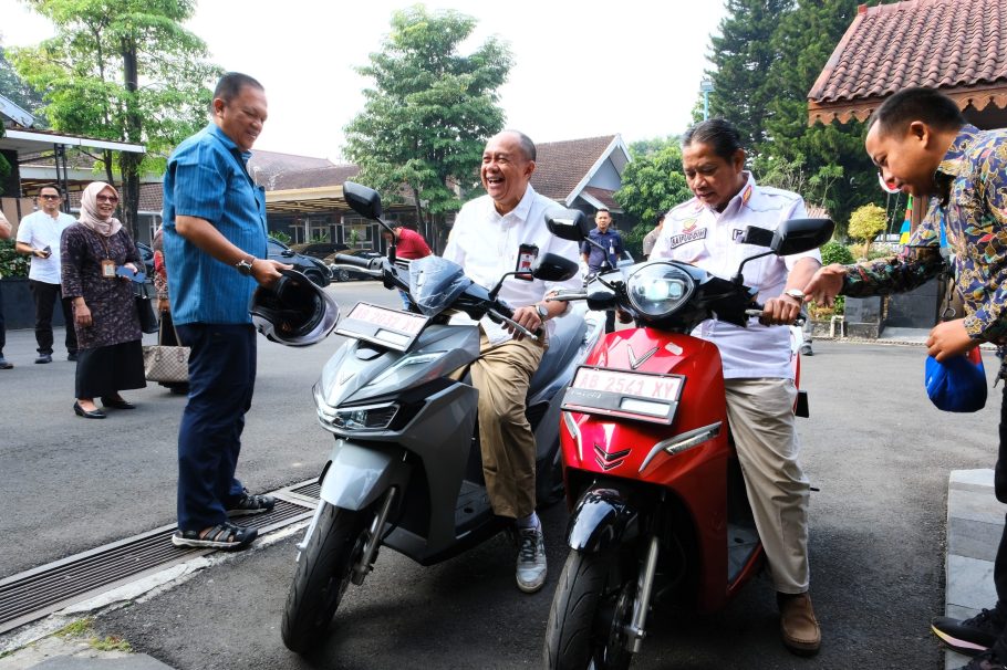 Bupati Banyumas Sadewo Tri Lastiono tertawa saat mencoba sepeda motor listrik VinFast warna abu-abu di Pendopo SiPanji Purwokerto.