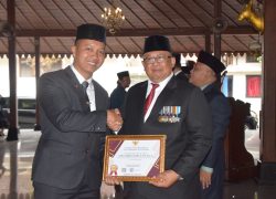 Sekda Banyumas Agus Nur Hadie menyerahkan piagam penghargaan Anugerah ASN Berprestasi 2026 kepada Tomi Luqman Hakim di Pendopo Si Panji Purwokerto.