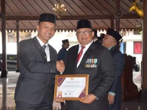 Sekda Banyumas Agus Nur Hadie menyerahkan piagam penghargaan Anugerah ASN Berprestasi 2026 kepada Tomi Luqman Hakim di Pendopo Si Panji Purwokerto.