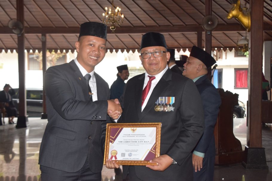 Sekda Banyumas Agus Nur Hadie menyerahkan piagam penghargaan Anugerah ASN Berprestasi 2026 kepada Tomi Luqman Hakim di Pendopo Si Panji Purwokerto.