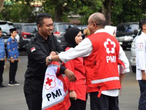 Bupati Banyumas Sadewo Tri Lastiono menyerahkan atribut PMI kepada relawan dalam Apel HUT ke-81 PMI di Pendopo Si Panji