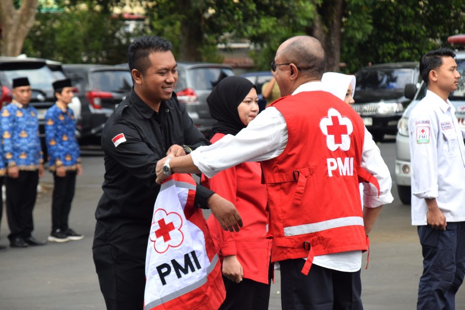 Bupati Banyumas Sadewo Tri Lastiono menyerahkan atribut PMI kepada relawan dalam Apel HUT ke-81 PMI di Pendopo Si Panji