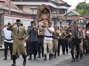 Peserta menggotong replika tandu Jenderal Soedirman didampingi rombongan berpakaian pejuang dalam Kirab Tandu Soedirman Banyumas di Alun-Alun Purwokerto.