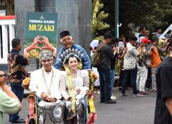 Pasangan pengantin busana adat Jawa diarak menggunakan becak hias dalam acara Nikah Gratis Banyumas Mantu 2026.