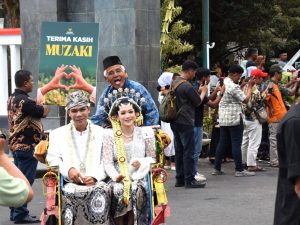 Pasangan pengantin busana adat Jawa diarak menggunakan becak hias dalam acara Nikah Gratis Banyumas Mantu 2026.